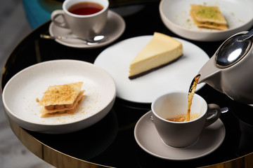 Woman hands with teapot pouring tea into cup, close-up