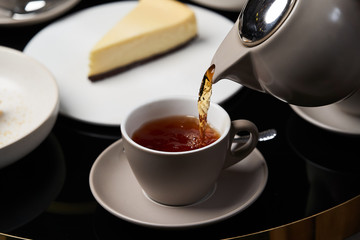 Woman hands with teapot pouring tea into cup, close-up