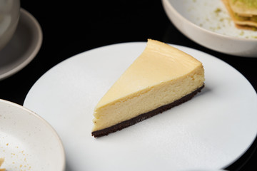 Cup of tea and slice of cheesecake on white plate on table