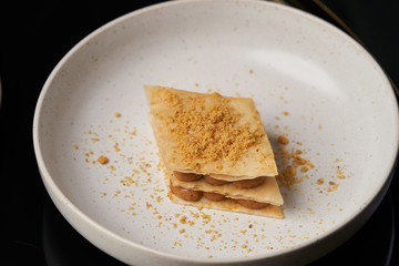 Cup of tea and slice of cheese cake on white plate on table