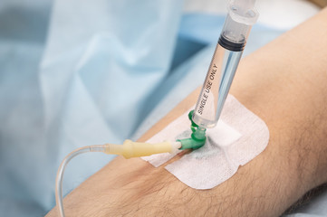 Single use syringe with medicine in catheter on man's hand