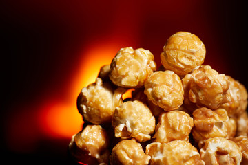 Appetizing caramelized popcorn with chocolate. Heap of homemade delicious popcorn on a black mirror background. Snacks and food for a movie theater or cinema. Fastfood background.