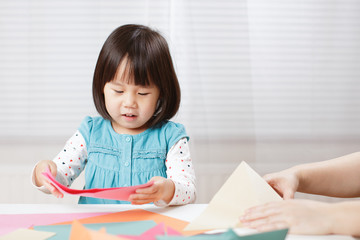toddler girl learn making  Origami at home against white background