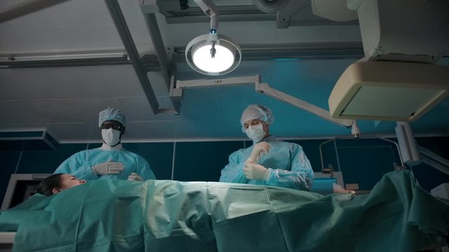 Dark-skinned surgeon jokingly beats a bit on the chest, his colleague is preparing for surgery.