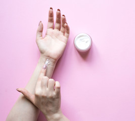 Natural Cosmetics for hand skin care with cream bottle, a means to reduce wrinkles on hands, moisturizing. Beautiful woman's hands on the pastel  pink background.
