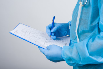 Coronavirus concept for blood test. A blue-gloved doctor holding a pen and completing a medical...