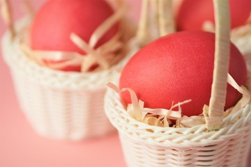 Pink chicken eggs in a white wicker basket covered with straw a bright pink background. Holiday card with space for text.Easter symbol.Copy space.
