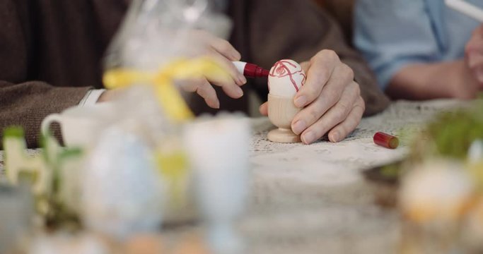 senior man and woman painting easter eggs