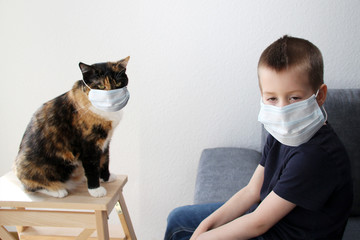 kid in the mask sits, folded his arms, in front of a silt is a pet cat in a respirator, the concept...
