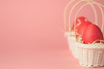Pink chicken eggs in a white wicker basket covered with straw a bright pink background. Holiday card with space for text.Easter symbol.Copy space.