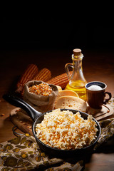 Appetizing salted popcorn with cheese. Heap of homemade delicious popcorn on a rustic wooden table. Snacks and food for a movie theater or cinema. Fastfood background. Frying pan with corn and oil. .