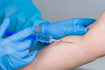 Medical doctor's hands in blue rubber gloves giving shot to patient, isolated white backgroud. Close up