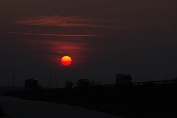 Sunset near the road. The big red sun at sunset. Background.