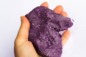 Children's creativity and motor development. Purple slime in hand on a white background.