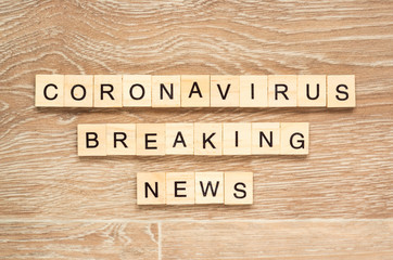 The words "Breaking Coronavirus News" spelt out with letter tiles on the wooden background