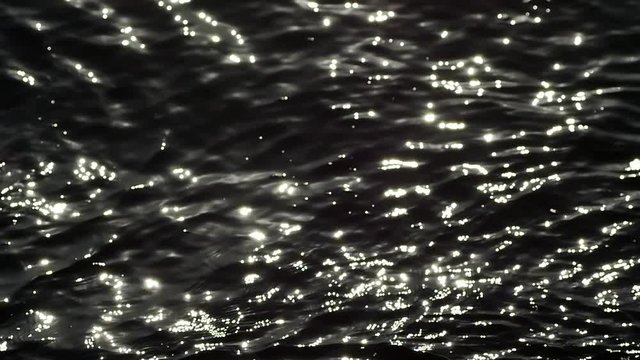 Looking over the calm water reflecting off the light. Slow Mo. High Contrast B&W Close Up Liquid Texture Seamless Loopable Abstract Motion Background. Shimmering and trembling ocean surface at sunset.