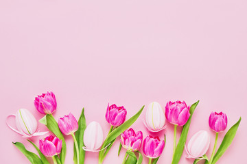 Easter background. Decorative pink Easter Eggs and tulip flowers on pink background. Top view, copy space. Easter celebration concept.