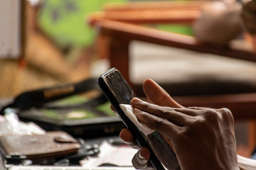 black man cleaning the surface of his mobile phone with a tissue