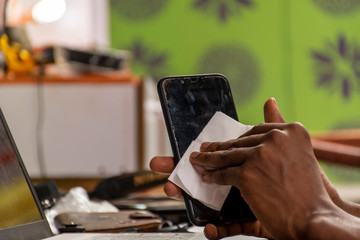 black man cleaning the surface of his mobile phone with a tissue