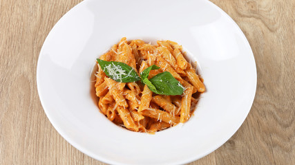 Shrimp pasta with basil leaves and Parmesan cheese in a white plate on a wooden background