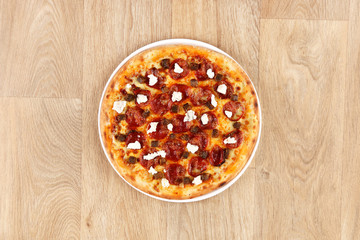 Pepperoni pizza with vegetables on a wooden background