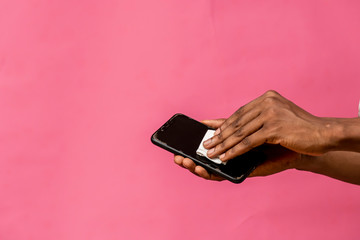 black man cleaning the surface of his mobile phone with a tissue