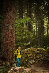 Naklejka na ściany i meble Pretty, young female hiker walking through a splendid old forest (shallow DOF)