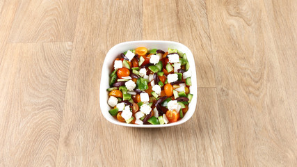 Mediterranean salad with fresh vegetables in a withe bowel  on a wooden background – Greece Salad