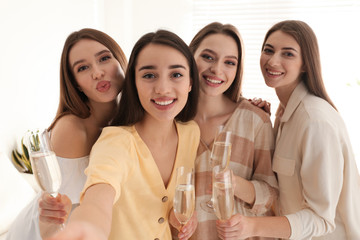 Beautiful young ladies with champagne taking selfie indoors. Woman's Day