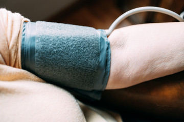 Close up of an old woman taking blood pressure using modern sphygmomanometer