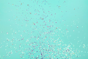 Holographic flying sparkles on blue festive background. Holiday backdrop for your projects.