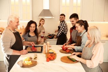 Happy people cooking food together in kitchen