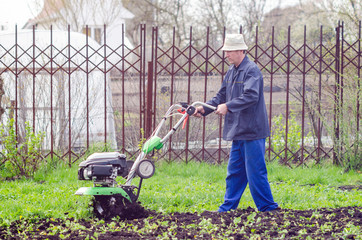 A man cultivates the land with a cultivator in a spring garden