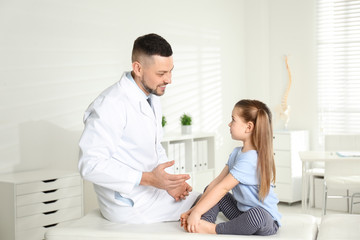 Obraz na płótnie Canvas Professional orthopedist examining little girl in clinic