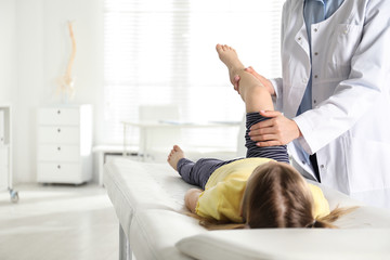 Professional orthopedist examining little patient's leg in clinic - obrazy, fototapety, plakaty