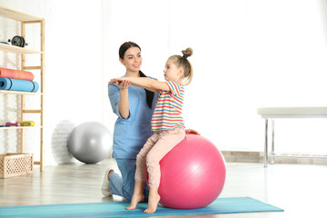 Fototapeta na wymiar Orthopedist working with little girl in hospital gym