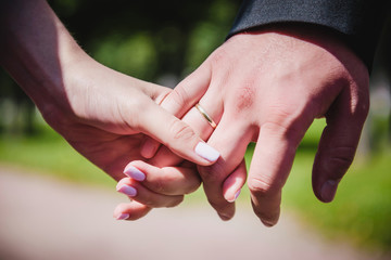 Bride and groom holding hands with wedding rings a nice manicure neat. Just married couple sitting in the park