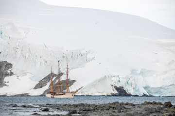 Obraz premium sailing Expedition ship in antarctica surrounded by ice in front of a glacier and rocks 
