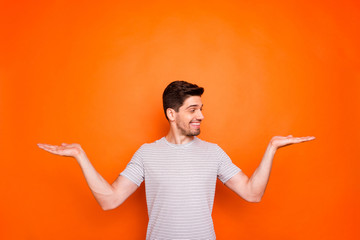 Photo of funny guy hold open palms hands advertising two new popular products low prices advising pick better one wear striped t-shirt isolated bright orange color background