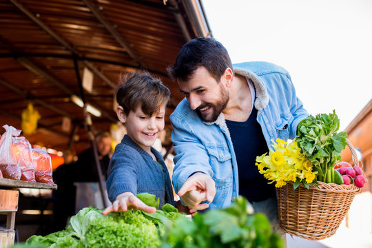 Family Buying Fresh Vegetables At Farmers Market Stall