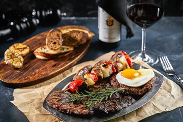 Grilled meat platter. Assorted delicious grilled meat with vegetables. Grilled mixed meat with pepper sauce and vegetables. Chef's hands spread meat on a plate