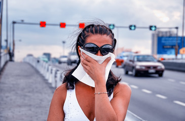 Woman covering her mouth with a napkin to prevent city air pollution