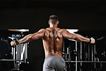 Naklejka na ściany i meble A man trains his arms and chest in the gym on the simulator, does exercises for different muscle groups. Fintes motivation, sports lifestyle, health, athletic body, body positive. Film grain