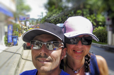 Happy couple of caucasian tourists visiting Thailand on a scooter