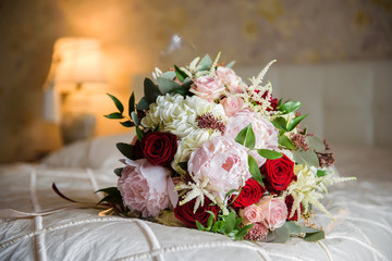 Colorful wedding bouquet on a bed. Bridal bouquet, white bedding. Luxury hotel room. Valentine's day or mother's day present