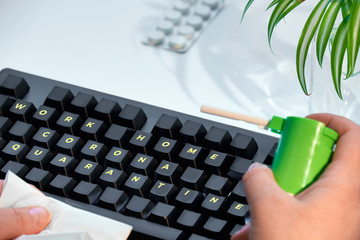 Working at home during coronavirus pandemic. Text "home office corona quarantine" on keys of keyboard. Pills, hands with throat spray, tissue. Quarantine yourself, help to flatten the curve
