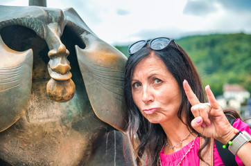 Beautiful woman on vacation joking and making grimaces in front of city landmark. Travel concept