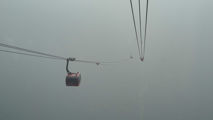 Fototapeta na wymiar Gondolas moving up a mountain in canada during a forest fire through smoke