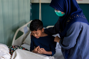 Muslim mother helping son put on mask at the hospital.