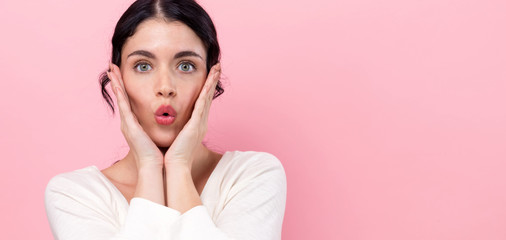 Surprised young woman posing on a pink background